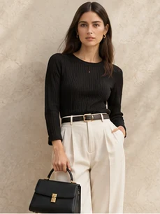 Structured black handbag carried by a model against a plaster wall