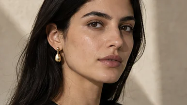 Gold drop earring worn, three-quarter portrait with the hair behind the ear